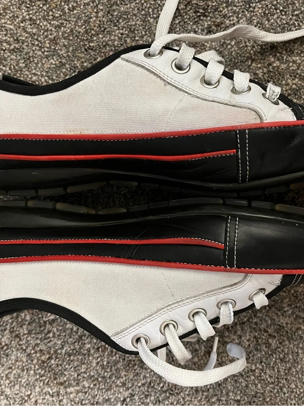 Donald J Pliner white canvas and black leather sneakers with red trim.